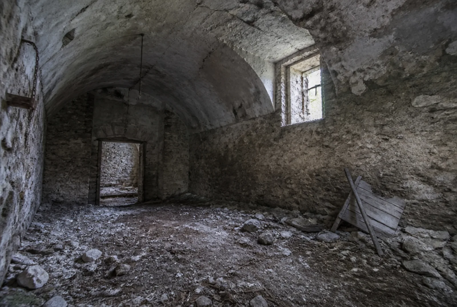 Il piano terra dell'ex stalla: volta a botte in muratura, calcinacci e pietre sulla terra battuta, la luce entra da una finestrella senza vetri