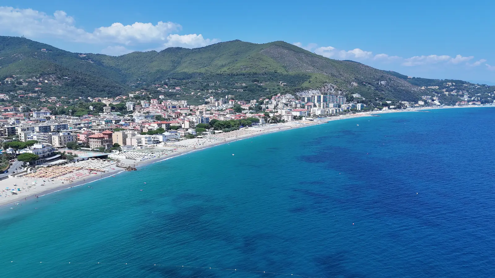 La baia del Golfo dell'Isola dal drone: la spiaggia, il paese e il crinale dietro, 28 luglio 2026